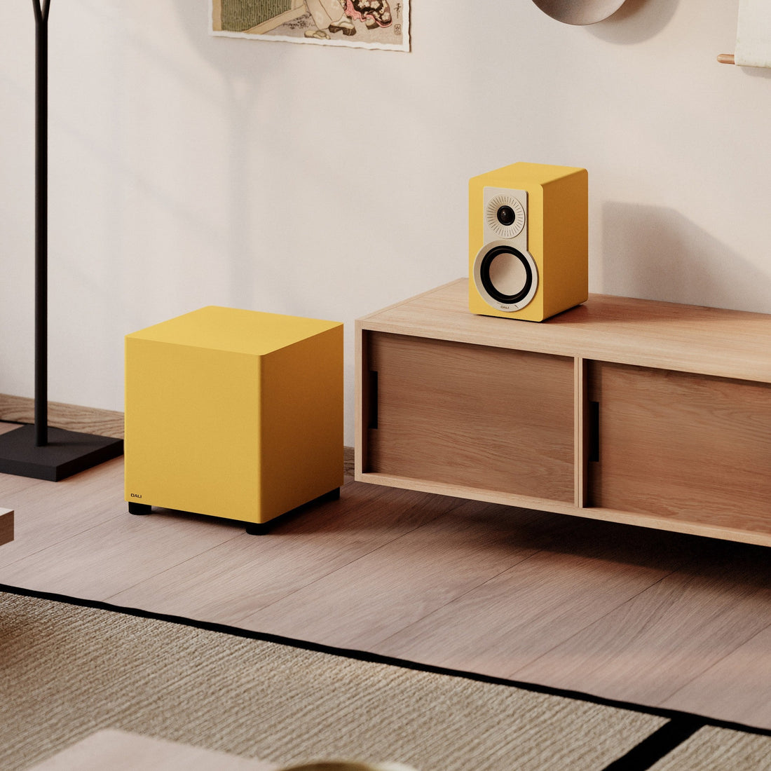 DALI Basik Sub in Golden Yellow beside a matching bookshelf speaker in a living room