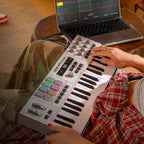 Akai Professional MPK Mini Plus II played on the couch next to a laptop