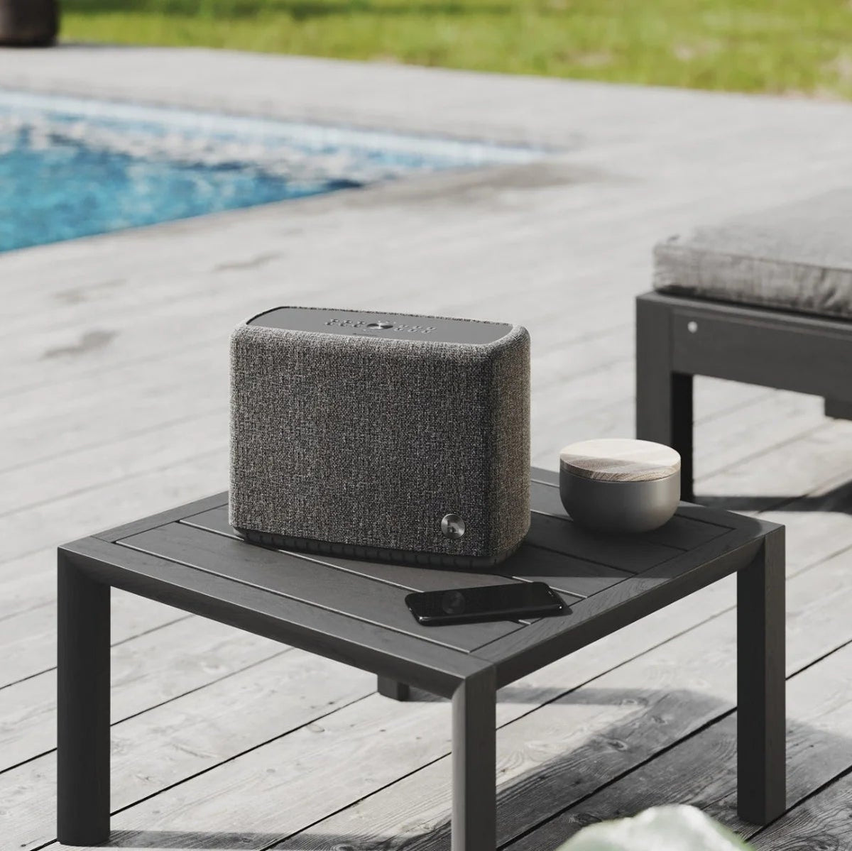 Audio Pro A15 portable speaker shown outdoors with rugged design, matte finish, and control buttons on top.