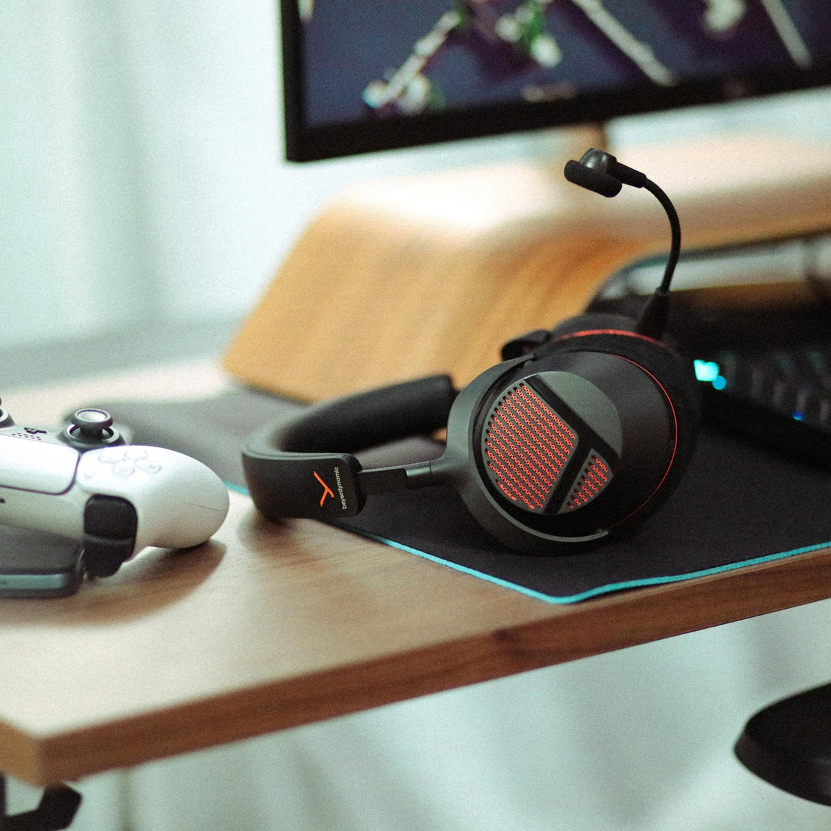 Beyerdynamic MMX 130 Wireless headset resting on a desk next to a game controller