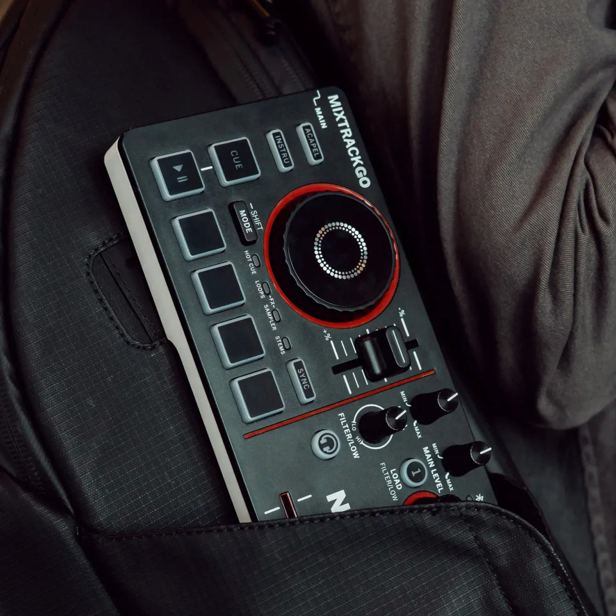 Numark Mixtrack Go tucked into a jacket pocket, showing its ultra-portable size