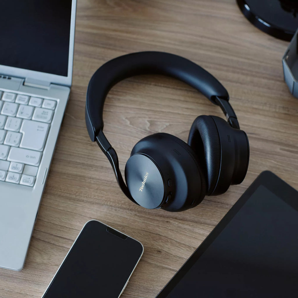 Technics EAH-A1000 in Black on a desk next to a laptop and phone